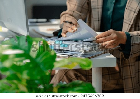 a secretary is organizing stack of paperwork for keep her desk clean, tidy up all finance document on desk because its so messy, a employee archive paper report for neat