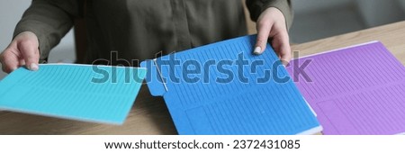 Secretary sorts colorful folders with accounting materials and documents on wooden table. Employee takes care of order at workplace in office Foto stock © 