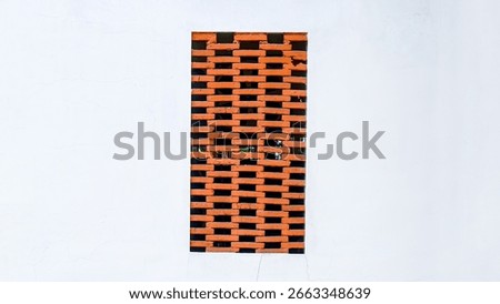 A section of brickwork forms an airy barrier within a building's wall, creating a balance between privacy and visibility. The contrasting brickwork and stucco creates an architectural focal point