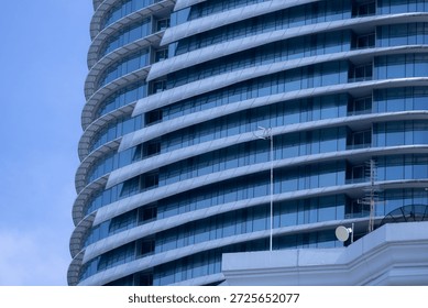 A section of a modern building with many rectangular glass windows reflecting the clear, bright blue sky.
