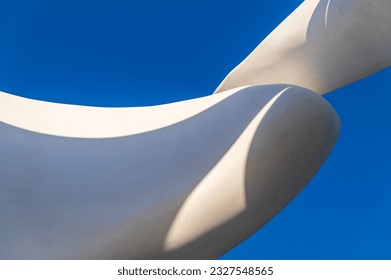 section of a sculpture making an abstract pattern of white curves with shadows