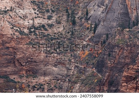 A section of Weeping Rock Trail as it cuts through steep canyon walls in a zig-zag pattern with colorful fall trees at Zion National Park, Utah.