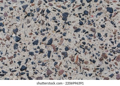 Section Of The Wet Ground Covered With The Old Concrete Made With Black And Red Granite Rubble Outdoors In Overcast Rainy Weather, Top View Close-up
