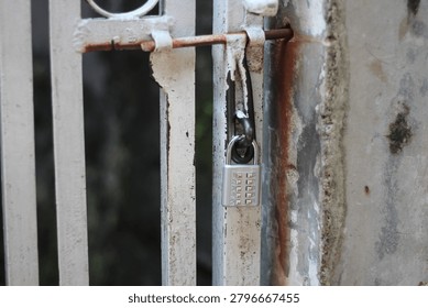 Secure combination padlock hanging on a metal gate focus on the numeric dial code