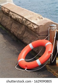 Secure Dependable Orange Public Life Preserver Leaning Against A Sandstone Wall.         