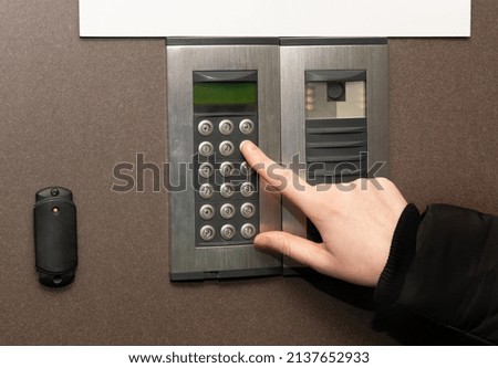 Secure home system. Hand pressing on intercom keypad, using door phone, doorphone, entryphone, videophone call
