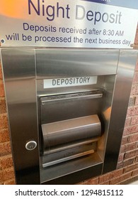 A secure night depository mechanism placed on the wall of a bank in vertical image format.