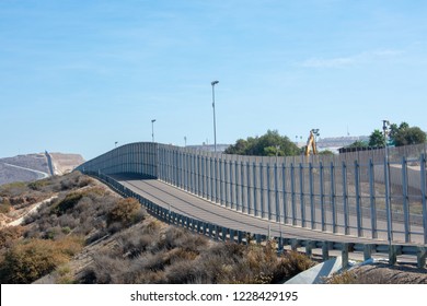 The Secured Border Fence And Path For United States Border Patrol Vehicles Stretches Into Horizon On The US - Mexico International Border In California