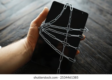 Secured Digital Device in Hand with Chains on Wooden Surface - Cybersecurity Concept