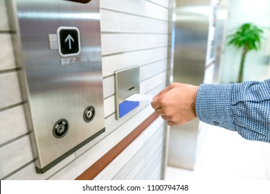 securing lift or elevator access control, man's hand is holding a key card lay up to insert in card hold for unlocking elevator doors before up or down. - Powered by Shutterstock