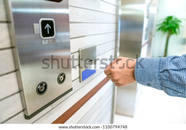 securing lift or elevator access control,\
man\'s hand is holding a key card lay up to insert in card hold for\
unlocking elevator doors before up or\
down.