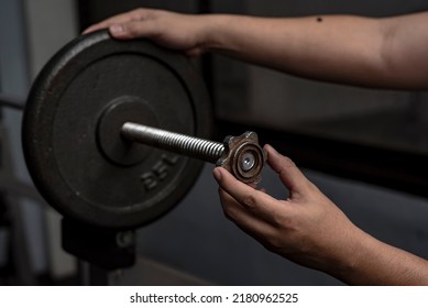 Securing a steel weight plate on a spinlock barbell bar with spinlock collars. Weightlifting and training safety concept