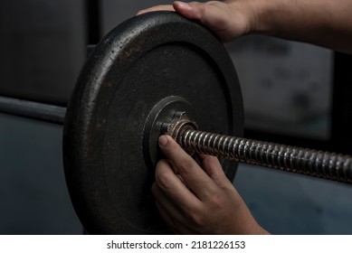 Securing a steel weight plate on a spinlock barbell bar by tightening a spinlock collar. Weightlifting and training safety concept