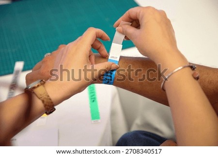 Securing a wristband, symbolizing entry and access. Captures the anticipation of events, festivals, and gatherings. Perfect for access control and event security.