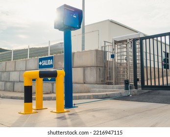 Security Access Door To A Restricted Industrial Area With An Optical Reader With Sun Flare And A Building On The Background