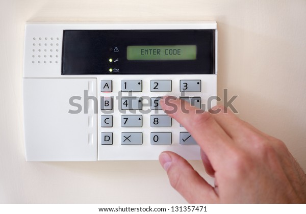 Security alarm\
keypad with person arming the\
system