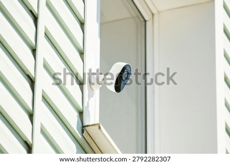 A security camera is installed on the side of a house.