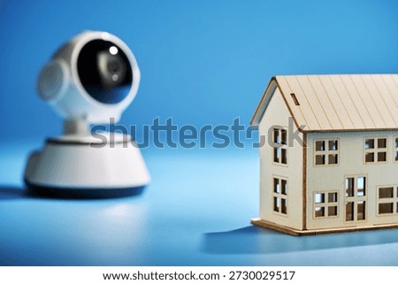 security camera and model house  on blue background.                  