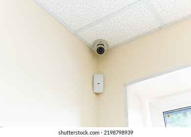 Security camera and motion detector installed on ceiling in room