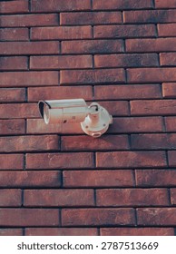 Security camera mounted on brick wall capturing surveillance