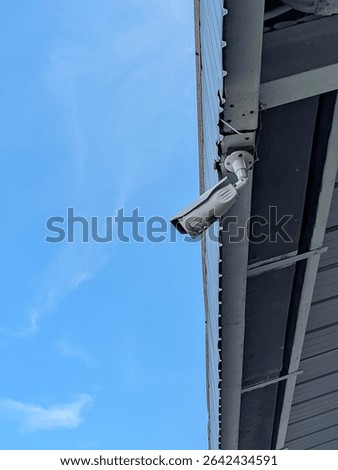 Security camera mounted on building exterior, blue sky background