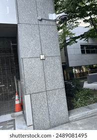 Security camera mounted on a modern building exterior in an urban setting, ensuring public safety and monitoring city activities.