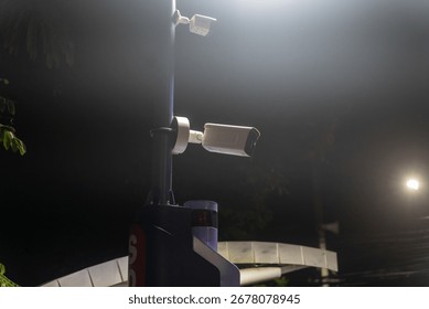 A security camera mounted on a pole captures the night scene, showcasing urban technology designed for surveillance and safety in low-light conditions.