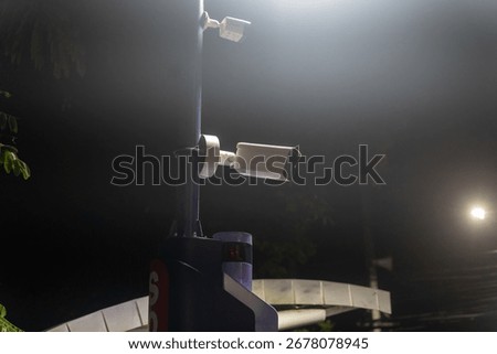 A security camera mounted on a pole captures the night scene, showcasing urban technology designed for surveillance and safety in low-light conditions.