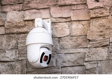 Security camera mounted on a rough stone wall, providing surveillance and emphasizing safety and monitoring technology