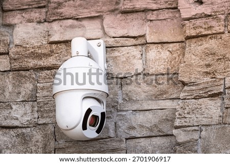 Security camera mounted on a rough stone wall, providing surveillance and emphasizing safety and monitoring technology