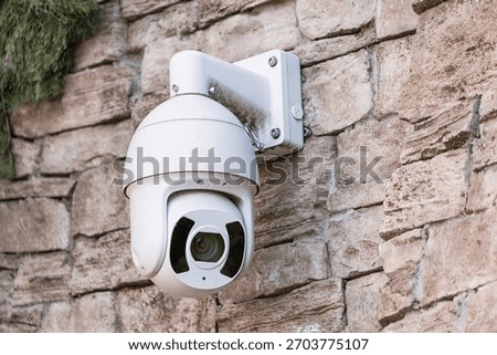 Security camera mounted on a rough stone wall, providing surveillance and emphasizing safety and monitoring technology