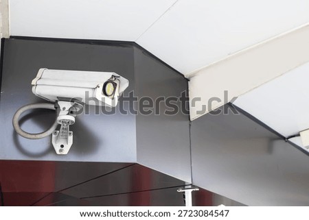 The security camera is mounted on top of a dark-colored wall on the exterior of the building.