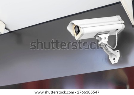 The security camera is mounted on top of a dark-colored wall on the exterior of the building.
