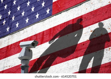Security camera on the border with painted Usa flag on textured cement wall and people shadows. Concept political relations with neighbors.