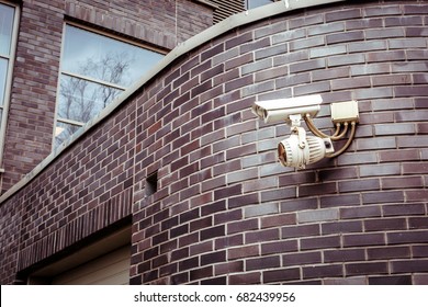 Security camera on the brick wall of building.