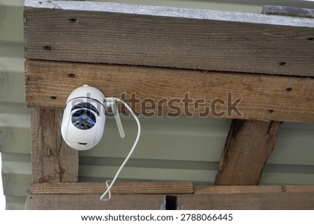 Security camera recording activities under a rustic wooden overhang for property protection