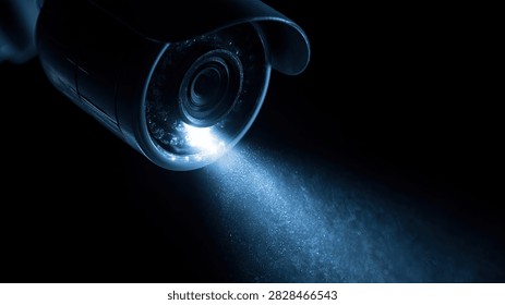 A security camera with a visible blue light beam, captured in a dark, atmospheric setting.