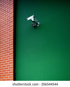 Security camera working on a green wall. Large copy space left for designer's needs