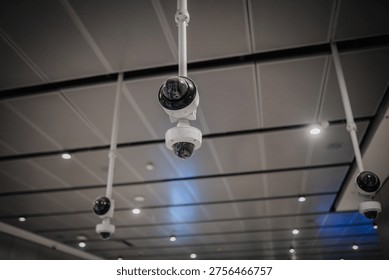 Security cameras are installed on the ceiling of a modern indoor area, capturing multiple angles with effective lighting for surveillance purposes