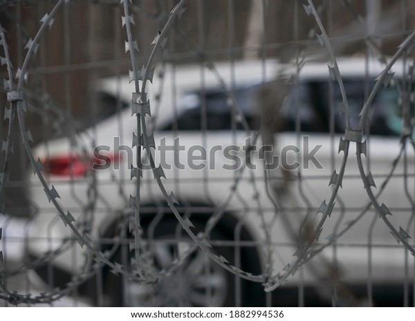 A security car hidden behind a metal fence evokes a\
feeling of isolation and danger.car arrest for debts. penalty\
parking. 