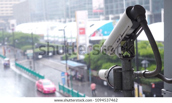 Security CCTV camera with blurred cars on road\
and human on\
background
