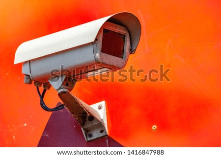 Security CCTV camera installed on a red wall in the city