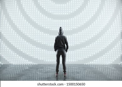 Security concept with hacker back staying on concrete floor opposite abstract digital wall.