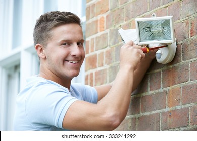 Security Consultant Fitting Security Light To House Wall