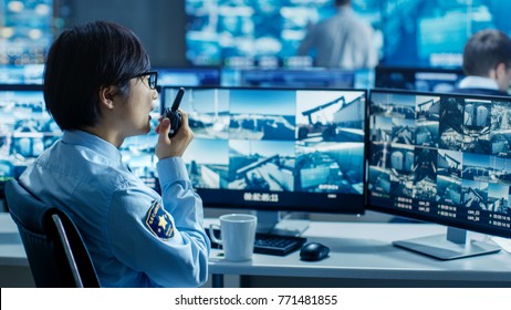 In the Security Control Room Officer Monitors Multiple Screens for Suspicious Activities, He Reports any Unauthorised Activities in His Walkie-Talkie. - Powered by Shutterstock