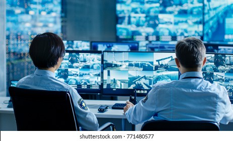 In the Security Control Room Two Officers Monitoring Multiple Screens for Suspicious Activities, They Report any Unauthorised Activities. They Guard Object of National Importance.