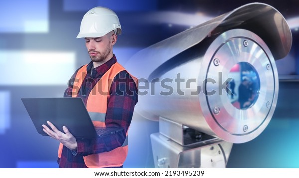 Security Engineer. Surveillance camera and man\
with laptop. Setting up video surveillance system. Video\
surveillance For security. Anti-vandal outdoor camera. Guy in\
orange vest and white\
helmet