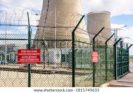 Security fence of a nuclear power plant in France with barbed wire and warning signs reading 