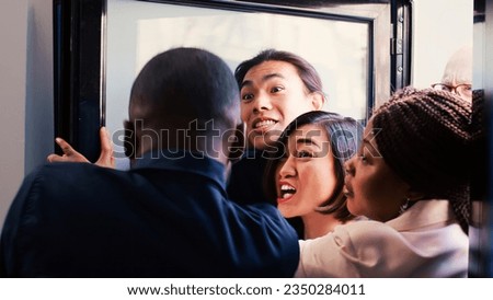 Security guard asking crowd to remain calm during black friday sales event, pushing people back and controlling clothing store entrance. Obsessed customers hunting for bargains, madness.