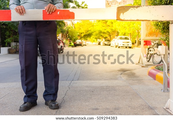 Security guard with barrier\
gate for access control at gateway , process in soft orange sun\
light style